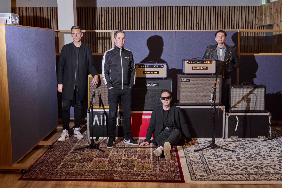 Los cuatro miembros de Glasvegas posan en un estudio de grabación en 2026, entre amplificadores