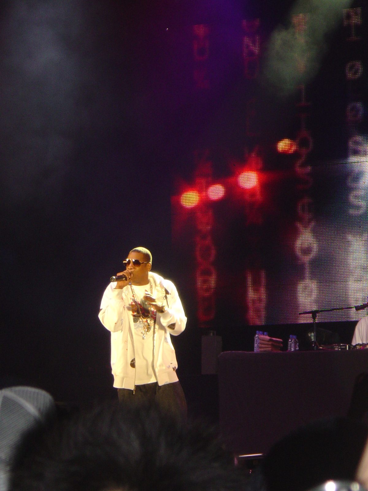 Jay-Z rapea con gafas de sol y sudadera blanca en un concierto de 2006